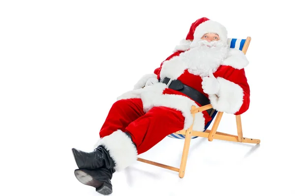 Santa claus mostrando polegar para cima e relaxante na cadeira de praia em branco — Fotografia de Stock