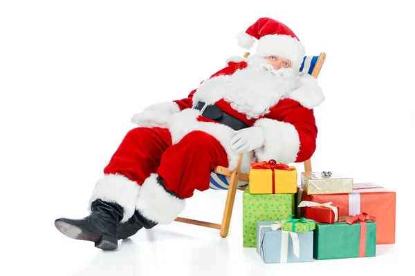 Santa claus relaxante na cadeira de praia com presentes de Natal no branco — Fotografia de Stock