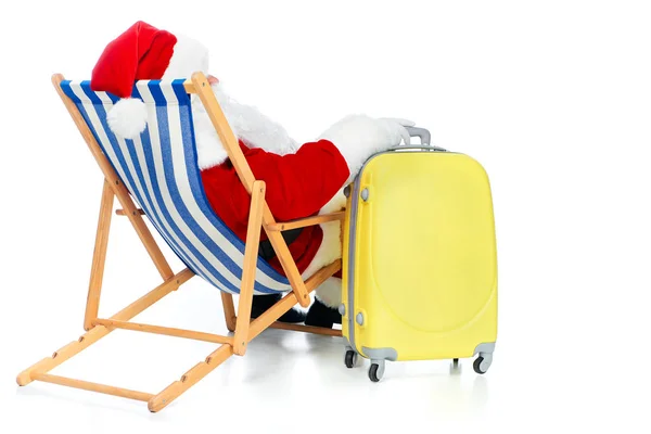 Vista posteriore di Babbo Natale che riposa sulla sedia da spiaggia con borsa da viaggio su bianco — Foto stock