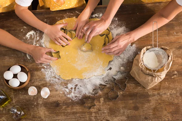 Cropped shot of child with mother and grandmother preparing cookies together in kitchen — Stock Photo