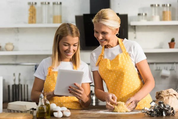 Heureux adulte mère et fille en utilisant tablette numérique tout en cuisinant ensemble — Photo de stock