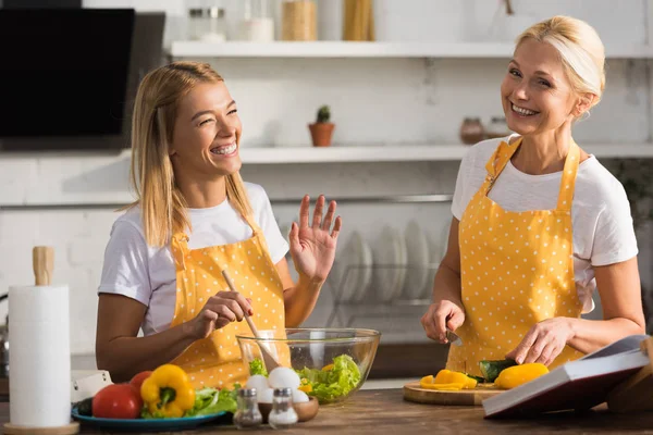 Glückliche reife Frau mit lächelnder erwachsener Tochter beim gemeinsamen Kochen von Gemüsesalat — Stockfoto