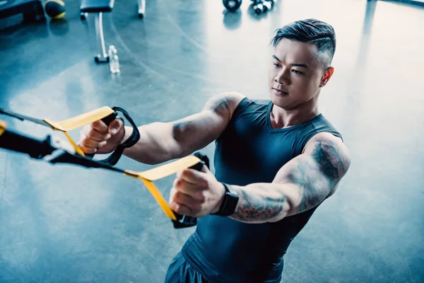Konzentriertes Training junger muskulöser Sportler mit Widerstandsbändern im Fitnessstudio — Stockfoto