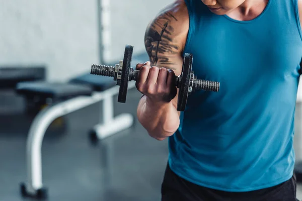 Close up view of young sportsman exercising with dumbbell in gym — Stock Photo