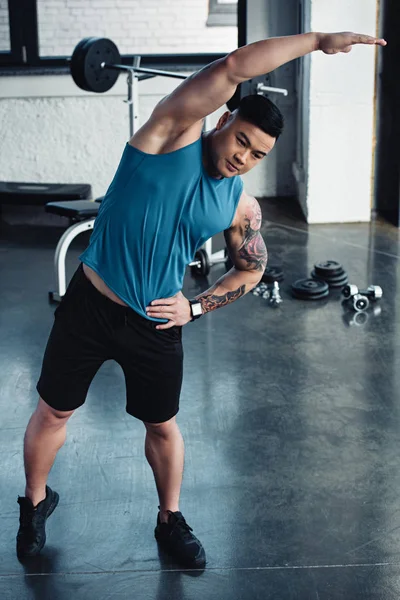 Joven deportista asain haciendo ejercicio de estiramiento en el gimnasio - foto de stock