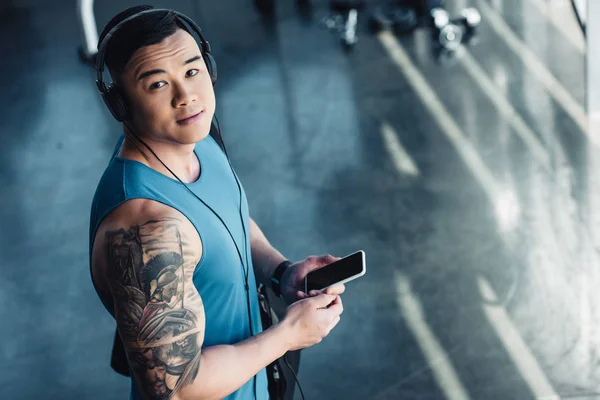 Young asian sportsman using smartphone and listening to music — Stock Photo