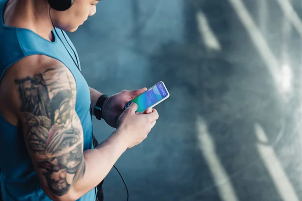 Young asian sportsman using smartphone with booking app and listening to music — Stock Photo