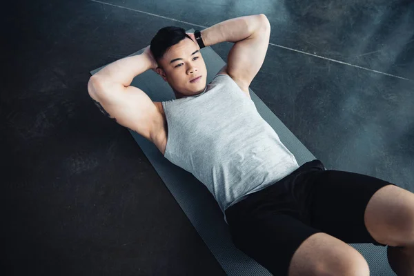 Junger asiatischer Sportler macht Bauchmuskeltraining auf Fitnessmatte im Fitnessstudio — Stockfoto