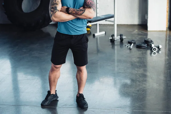 Vue recadrée d'un jeune sportif aux bras croisés au gymnase — Photo de stock