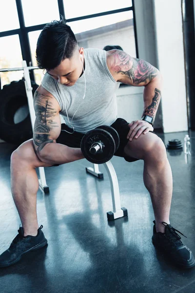 Concentrated young sportsman exercising with dumbbell in gym — Stock Photo