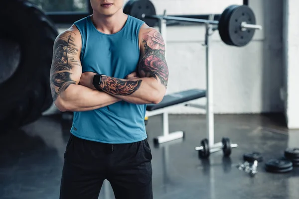 Cropped view of young sportsman with crossed arms at gym — Stock Photo