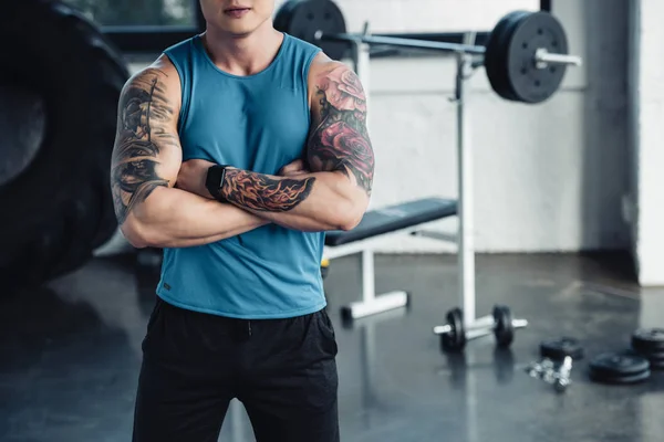 Vue recadrée d'un jeune sportif aux bras croisés au gymnase — Photo de stock