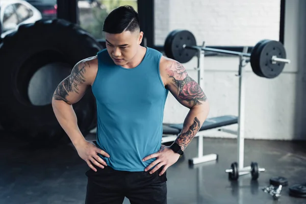 Young asian sportsman with hands on hips at gym — Stock Photo