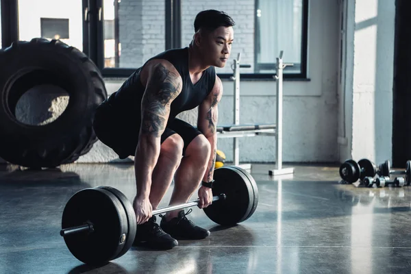 Focused muscular sportsman training with barbell at gym — Stock Photo