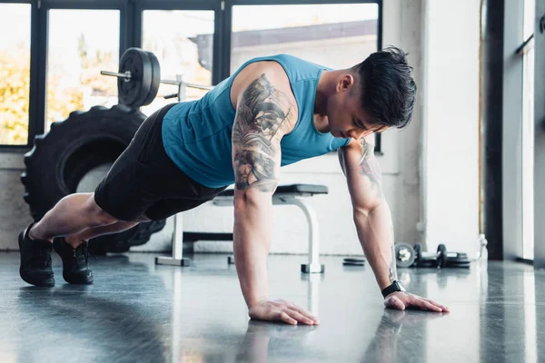 Muscoloso giovane sportivo che fa esercizio di plancia in palestra — Foto stock