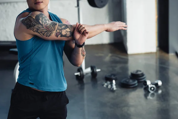 Cropped view of young sportsman doing stretching exercise at gym — Stock Photo