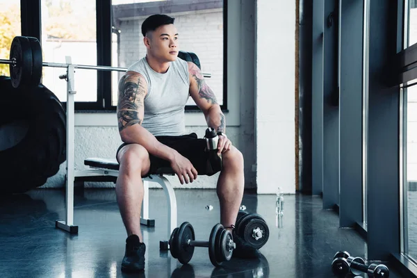 Joven deportista concentrado haciendo ejercicio con pesas en el gimnasio - foto de stock