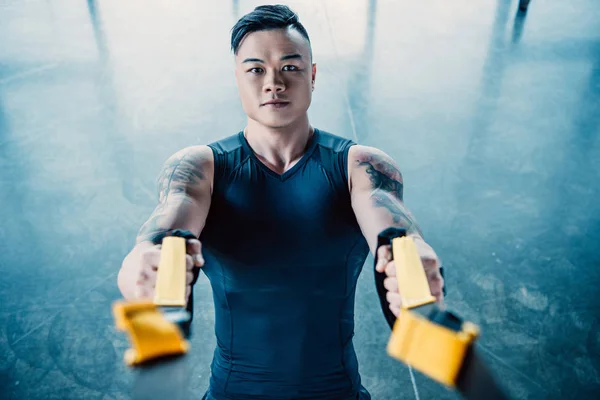 Concentré jeune musclé asain sportif entraînement avec des bandes de résistance dans la salle de gym — Photo de stock