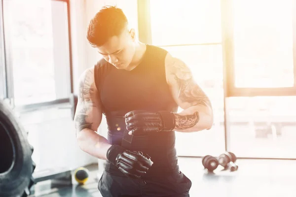 Joven deportista asain con guantes de boxeo negro en el gimnasio a la luz del sol - foto de stock