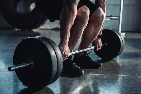 Cropped view of muscular sportsman exercising with barbell at gym — Stock Photo