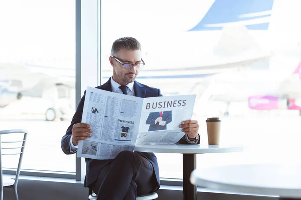 Adulto hombre de negocios leyendo periódico en la cafetería en el aeropuerto - foto de stock