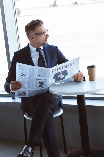 Uomo d'affari adulto che legge il giornale e guarda la finestra all'aeroporto — Foto stock
