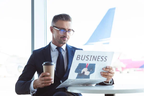 Adulte beau homme d'affaires lisant le journal et tenant le café pour aller à l'aéroport — Photo de stock
