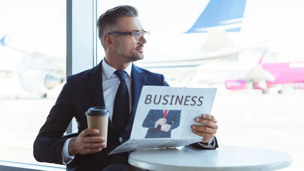 Adulte bel homme d'affaires avec café pour aller lire le journal et regarder la fenêtre à l'aéroport — Photo de stock