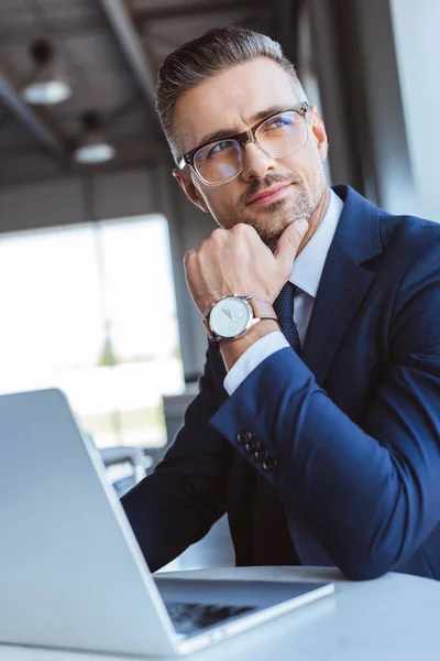 Дорослий бізнесмен в окулярах годинник, використовуючи ноутбук в аеропорту — стокове фото