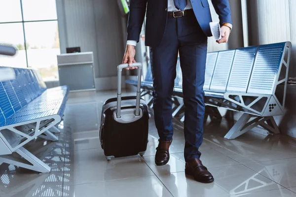 Primer plano de hombre de negocios con el equipaje caminando a lo largo de la sala de salida en el aeropuerto - foto de stock
