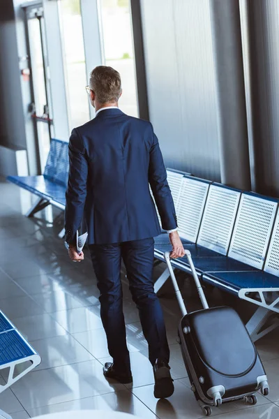Vue arrière de l'homme d'affaires avec sac de voyage marchant à l'aéroport — Photo de stock