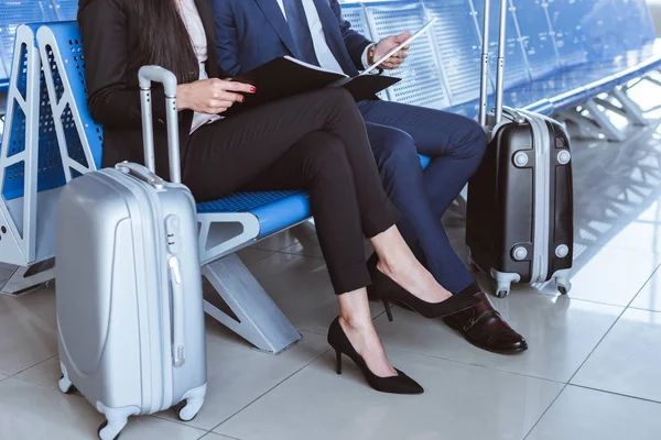 Крупним планом бізнесмен використовує цифровий планшет, в той час як бізнес-леді тримає чорну теку в залі вильоту в аеропорту — стокове фото