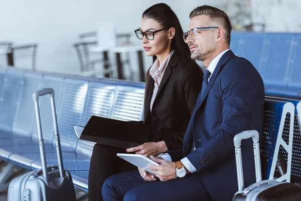 Adult businessman and businesswoman sitting at departure lounge in airport — Stock Photo