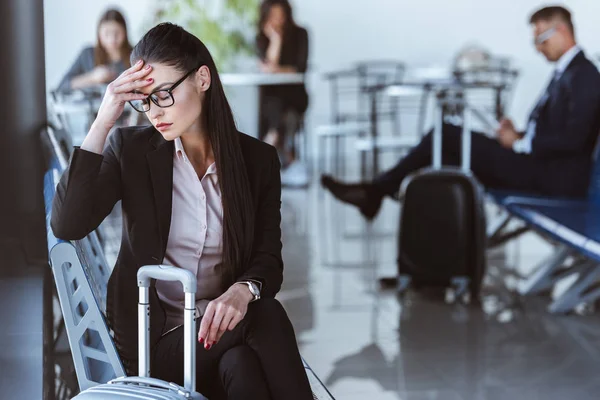 Müde Geschäftsfrau sitzt in Abflughalle am Flughafen — Stockfoto