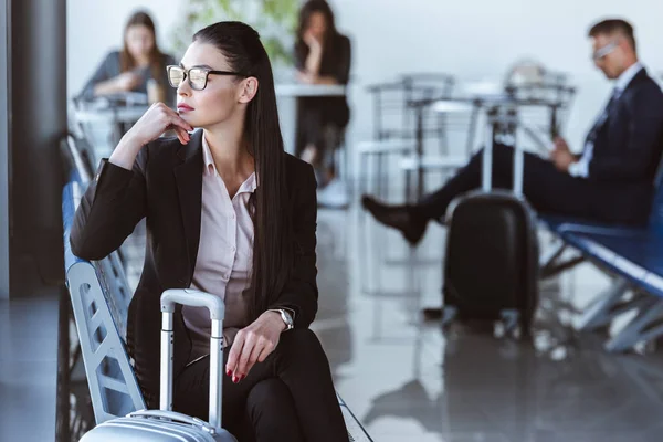 Mujer de negocios adulta sentada en la sala de salida en el aeropuerto - foto de stock