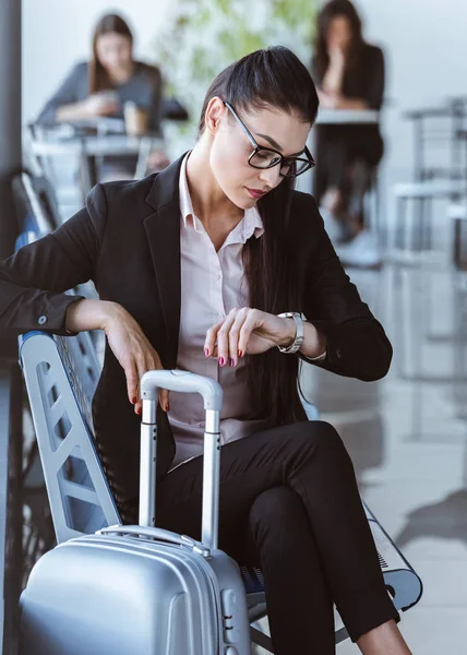 Erwachsene Geschäftsfrau schaut auf Uhr und wartet auf Abflug am Flughafen — Stockfoto