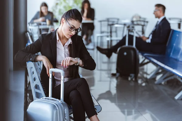 Доросла бізнес-леді дивиться дивитися і чекає вильоту в аеропорту — стокове фото