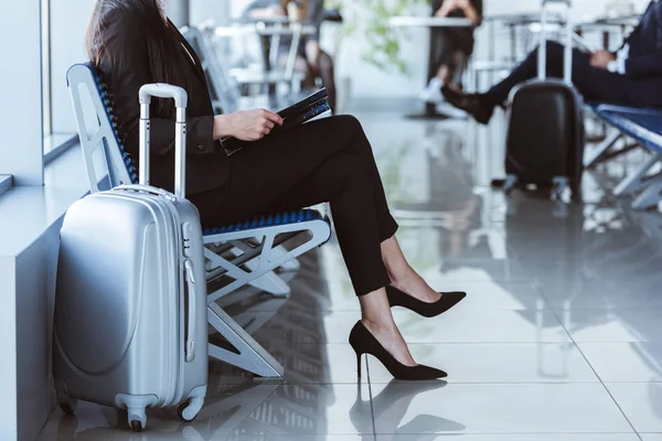 Mujer de negocios con carpeta negra sentada en la sala de salida en el aeropuerto - foto de stock
