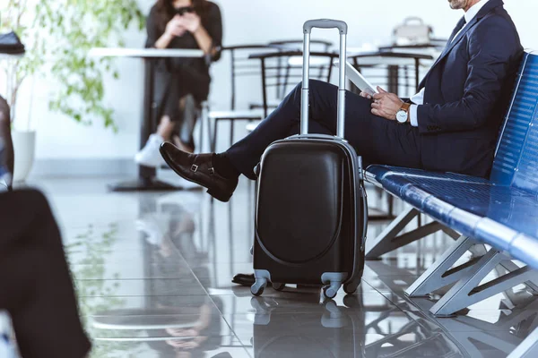 Hombre de negocios con tableta digital sentado en la sala de salida en el aeropuerto - foto de stock