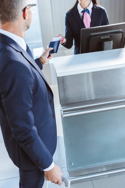 Бизнесмен, предоставляющий документы работнице аэропорта при регистрации в аэропорту — стоковое фото