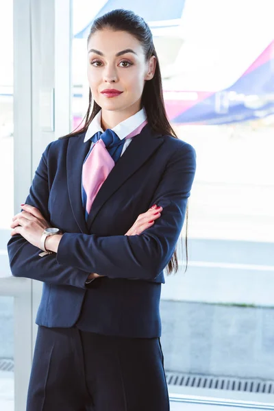 Adult female airport worker standing with arms crossed near window — Stock Photo