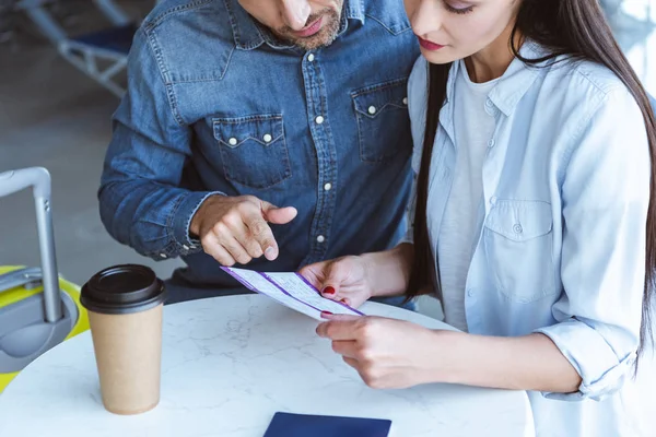 Erwachsenes Paar sitzt mit Tickets in der Abflughalle des Flughafens — Stockfoto