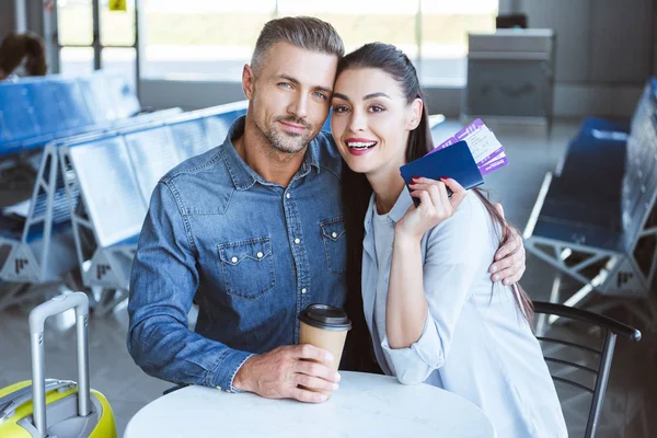 Pareja sentada en el aeropuerto con café, pasaporte y billete - foto de stock