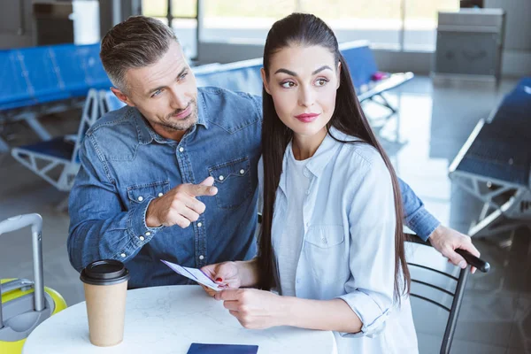 Mann zeigt auf etwas und Frau schaut sich das am Flughafen an — Stockfoto