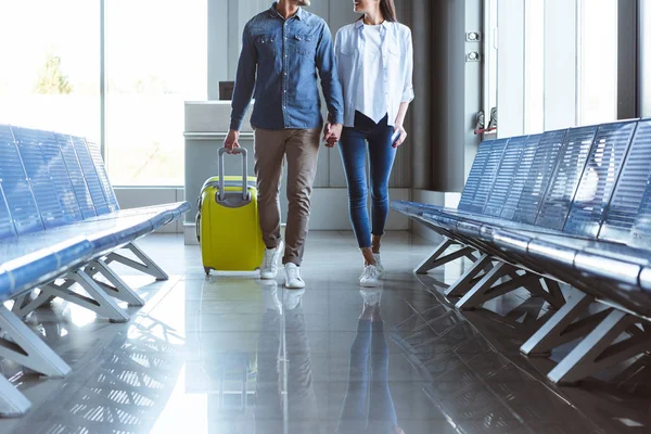 Pareja con maleta amarilla en movimiento en el aeropuerto - foto de stock