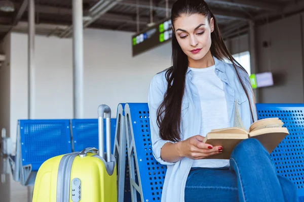 Frau liest Buch und wartet am Flughafen auf ihr Flugzeug — Stockfoto