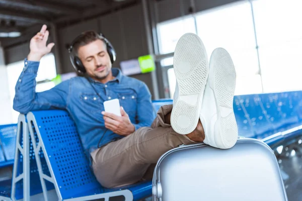 Человек наслаждается музыкой и расслабляется в ожидании своего рейса в аэропорту — стоковое фото