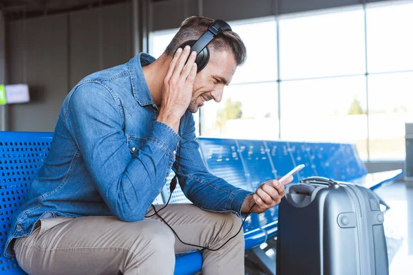 Mann wartet am Flughafen und hört Musik — Stockfoto