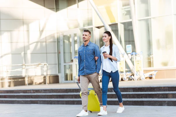 Couple of tourists with yellow suitcase leaving the airport — Stock Photo