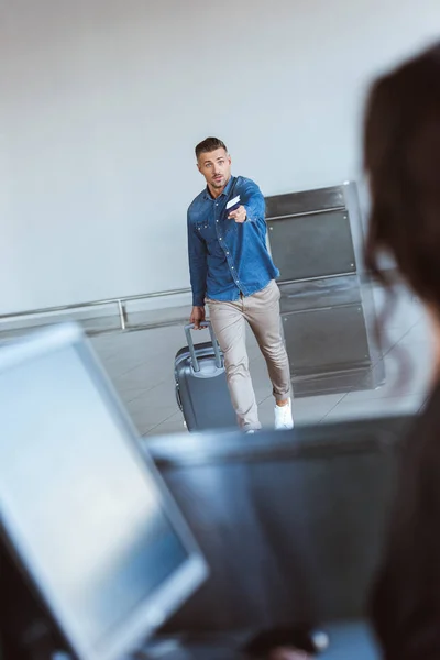 Турбуються дорослий чоловік з hurring багажу, outstretching паспорт і повітря квитки в аеропорту — стокове фото